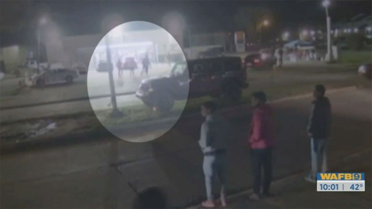 Images de sécurité montrant une jeune femme marchant derrière quatre hommes dans un parking très fréquenté.