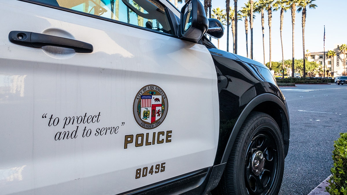 Los Angeles, États-Unis - Gros plan sur l'insigne et le slogan d'un véhicule LAPD, avec le reflet de la tour Union Stations visible dans la fenêtre des voitures.