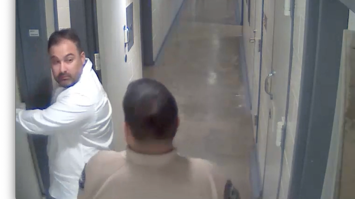 Joseph Iniguez regarde par-dessus son épaule un policier alors qu'il entre dans une cellule