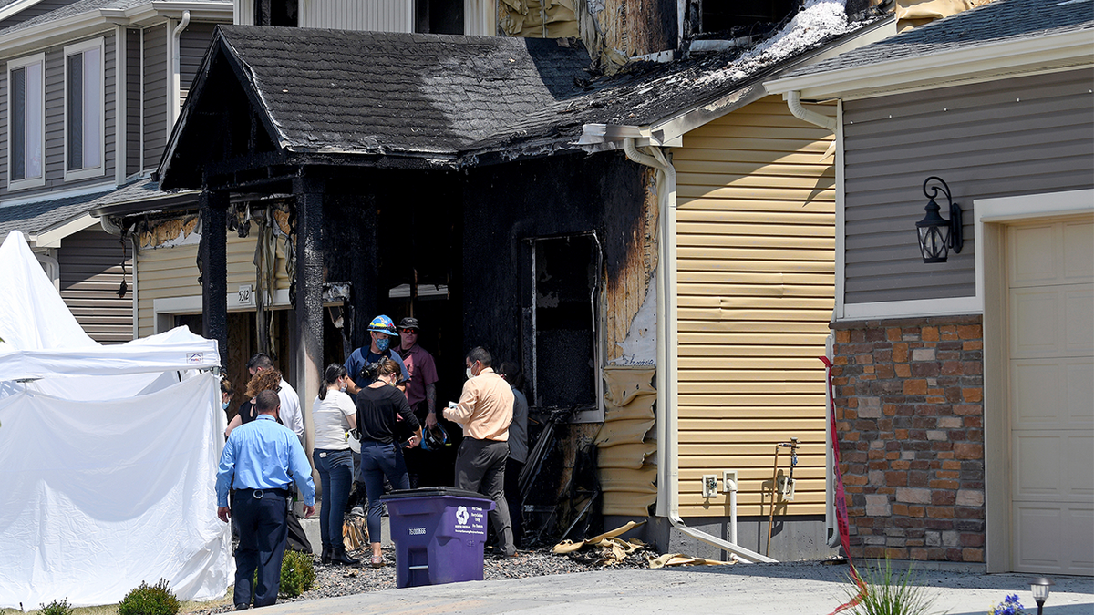 Des enquêteurs se tiennent devant une maison où cinq personnes ont été tuées dans un incendie